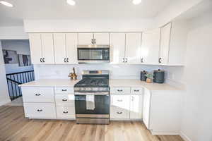 Kitchen with stainless steel appliances, white cabinetry, and light hardwood / wood-style floors