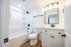 Full bathroom with vanity, wood-type flooring, shower / bathtub combination, and toilet