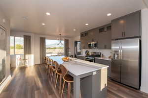 Kitchen with a center island with sink, a breakfast bar area, dark wood-type flooring, sink, and stainless steel appliances