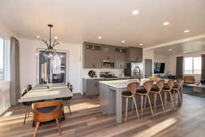 Kitchen with gray cabinets, a kitchen island with sink, hardwood / wood-style flooring, and appliances with stainless steel finishes