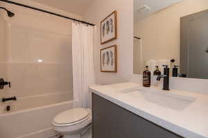 Full bathroom featuring vanity, shower / bath combination with curtain, and toilet