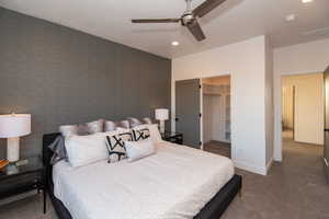 Bedroom featuring a spacious closet, ceiling fan, a closet, and dark carpet