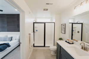 Bathroom with vanity, toilet, walk in shower, and tile patterned flooring