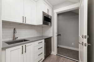 Kitchen featuring decorative backsplash, stainless steel appliances, sink, and white cabinetry