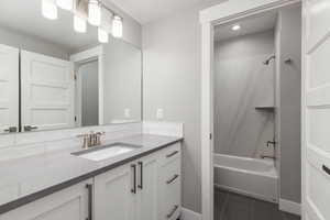 Bathroom with vanity, bathtub / shower combination, and tile patterned flooring