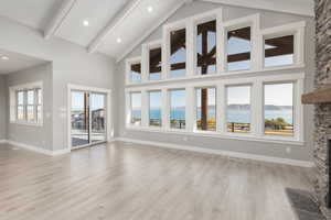 Unfurnished living room featuring a water view, light waterproof laminate flooring, and a wealth of natural light, and a fireplace