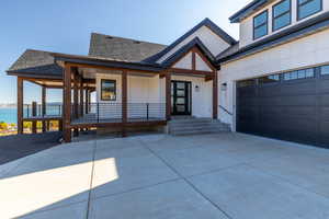 View of front of house with a water view, a porch, and a garage