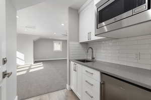 Kitchen featuring stone countertops, stainless steel microwave,  sink, and white cabinetry