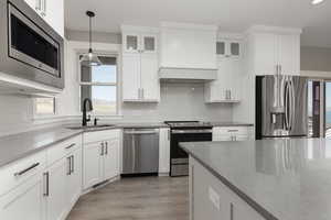 Kitchen featuring appliances with stainless steel finishes, light waterproof laminate flooring, white cabinetry, and sink