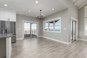 Unfurnished dining area featuring a notable chandelier and light waterproof laminate flooring