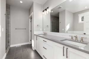 Primary bathroom with vanity, walk in shower, and tile patterned flooring