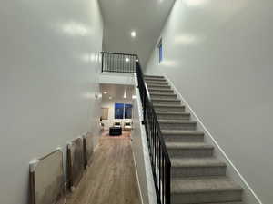 Staircase with wood-type flooring and a towering ceiling