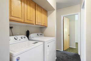 Laundry room with cabinets, washer and clothes dryer, and dark colored carpet