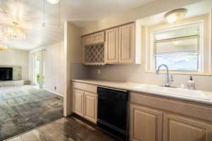 Kitchen with black dishwasher, dark hardwood / wood-style flooring, plenty of natural light, and decorative light fixtures