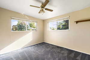 Spare room with ceiling fan and dark carpet