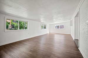 Spare room with a textured ceiling, a healthy amount of sunlight, and dark hardwood / wood-style flooring