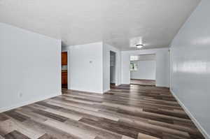 Unfurnished living room featuring dark hardwood / wood-style floors and a textured ceiling