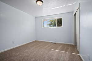 Unfurnished bedroom featuring a closet, a textured ceiling, and carpet