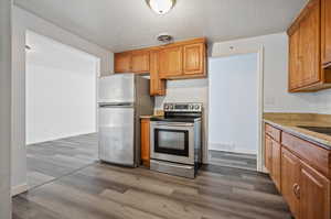 Kitchen featuring a textured ceiling, appliances with stainless steel finishes, and wood-type flooring