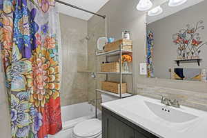 Full bathroom featuring backsplash, vanity, shower / tub combo, and toilet