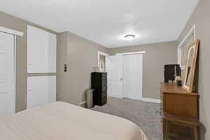 Carpeted bedroom featuring a textured ceiling and two closets