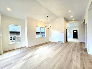 Interior space featuring an inviting chandelier, light hardwood / wood-style floors, vaulted ceiling, and a wealth of natural light