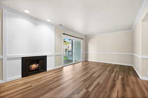 Unfurnished living room featuring ornamental molding and wood-type flooring