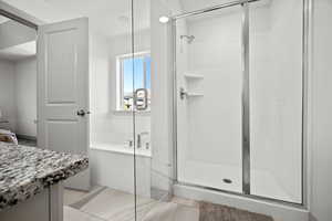 Bathroom with a garden tub, light tile patterned floors, a stall shower, and vanity