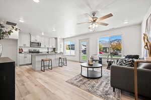 Living room with light wood-type flooring, ceiling fan, and recessed lighting
