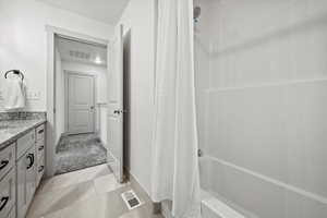 Full bath featuring vanity, shower / bath combination with curtain, light tile patterned flooring, and light carpet