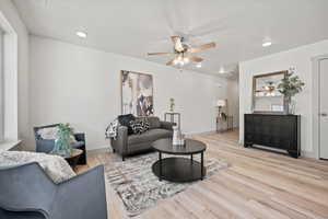 Living area featuring light wood-type flooring, a ceiling fan, and recessed lighting