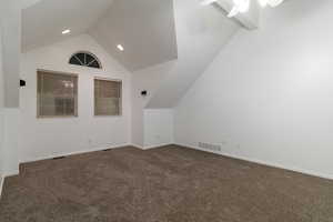 Additional living space featuring ceiling fan, lofted ceiling, and dark carpet