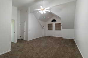 Additional living space with lofted ceiling, ceiling fan, and dark colored carpet