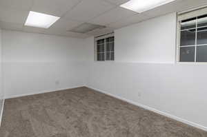 Carpeted spare room featuring a drop ceiling