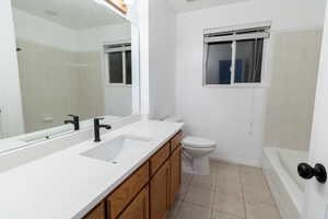 Full bathroom with vanity, toilet, tiled shower / bath combo, and tile patterned floors