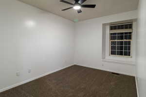 Unfurnished room with ceiling fan and dark carpet