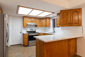 Kitchen with sink, decorative backsplash, kitchen peninsula, and stainless steel appliances