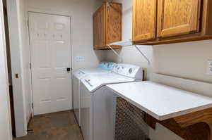 Laundry room featuring independent washer and dryer, cabinets, and a barn door