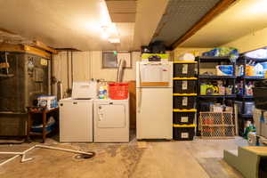 Basement featuring washer and clothes dryer and white fridge