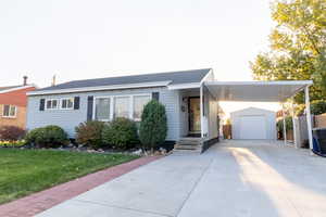 Ranch-style house featuring a front yard, an outbuilding, and a garage