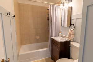 Full bathroom with vanity, shower / bath combo with shower curtain, and toilet