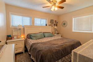 Bedroom with ceiling fan and a textured ceiling