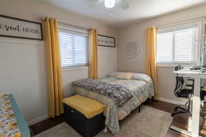 Bedroom with ceiling fan, hardwood / wood-style flooring, multiple windows, and wooden walls