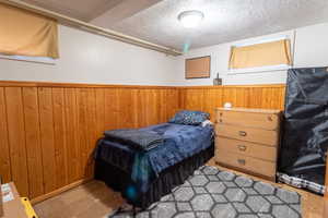 Bedroom with wood walls and a textured ceiling