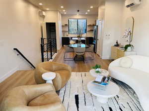 Living room with light wood-type flooring and an AC wall unit