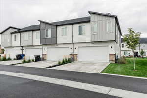 Multi unit property featuring a garage, cooling unit, and a front lawn