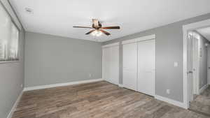 Unfurnished bedroom with hardwood / wood-style floors, multiple closets, and ceiling fan