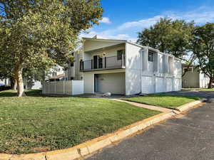 View of front facade with a front lawn, a garage, and a balcony