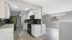 Kitchen with light hardwood / wood-style flooring, white cabinets, black appliances, and backsplash