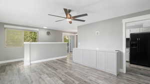 Empty room with light hardwood / wood-style floors, ceiling fan, and a wealth of natural light